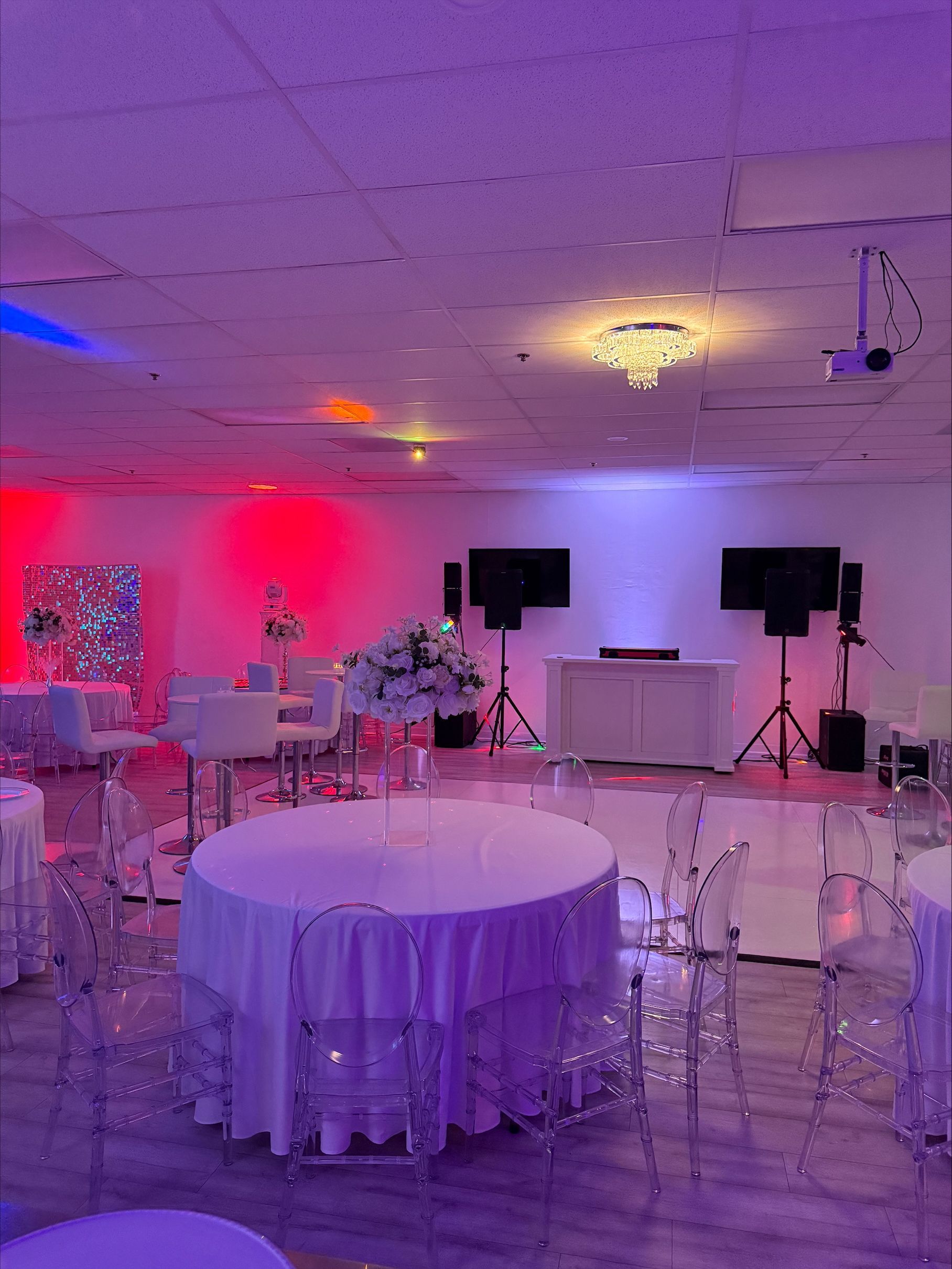 A large room with tables and chairs and purple lights.