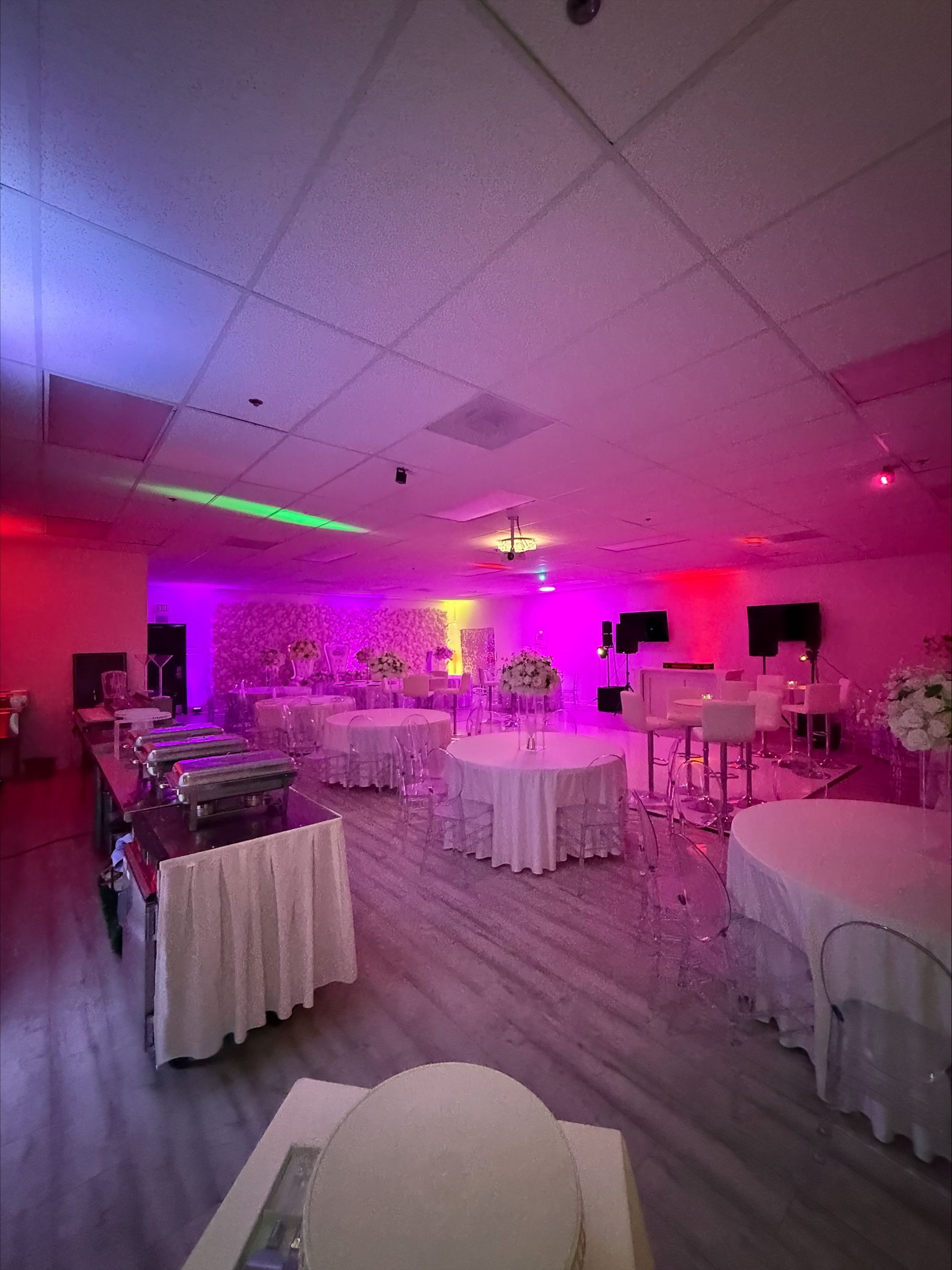 A large room filled with tables and chairs and purple and green lights.