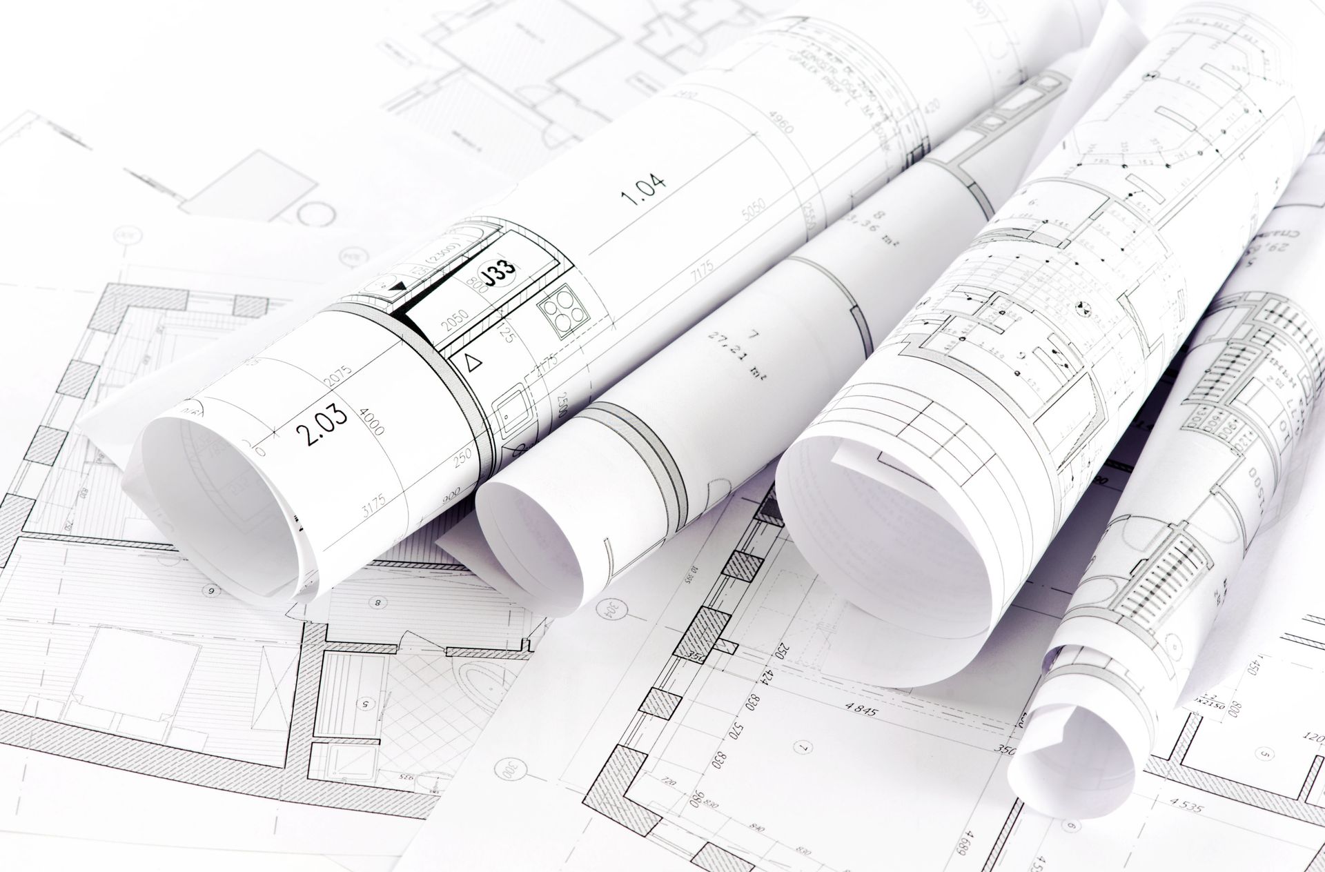 Rolled blueprints and open architectural plans, detailed black and white drawings, on a white surface.