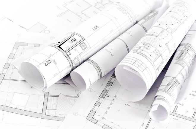 Rolled blueprints and open architectural plans, detailed black and white drawings, on a white surface.