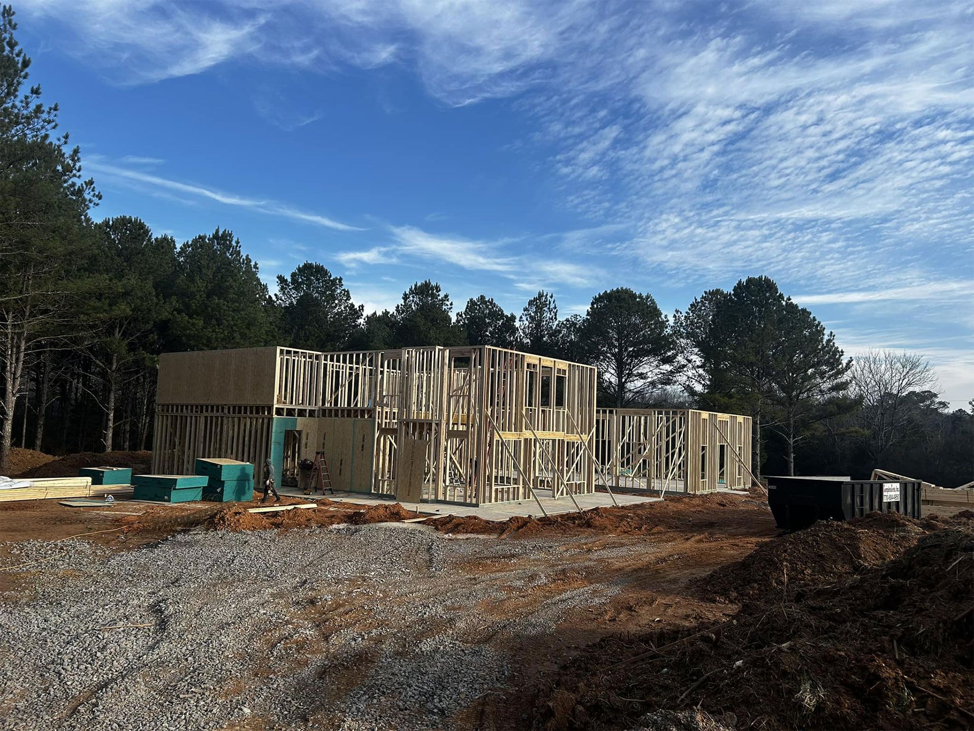 Two-story house under construction, exposed wooden frame against a clear blue sky.