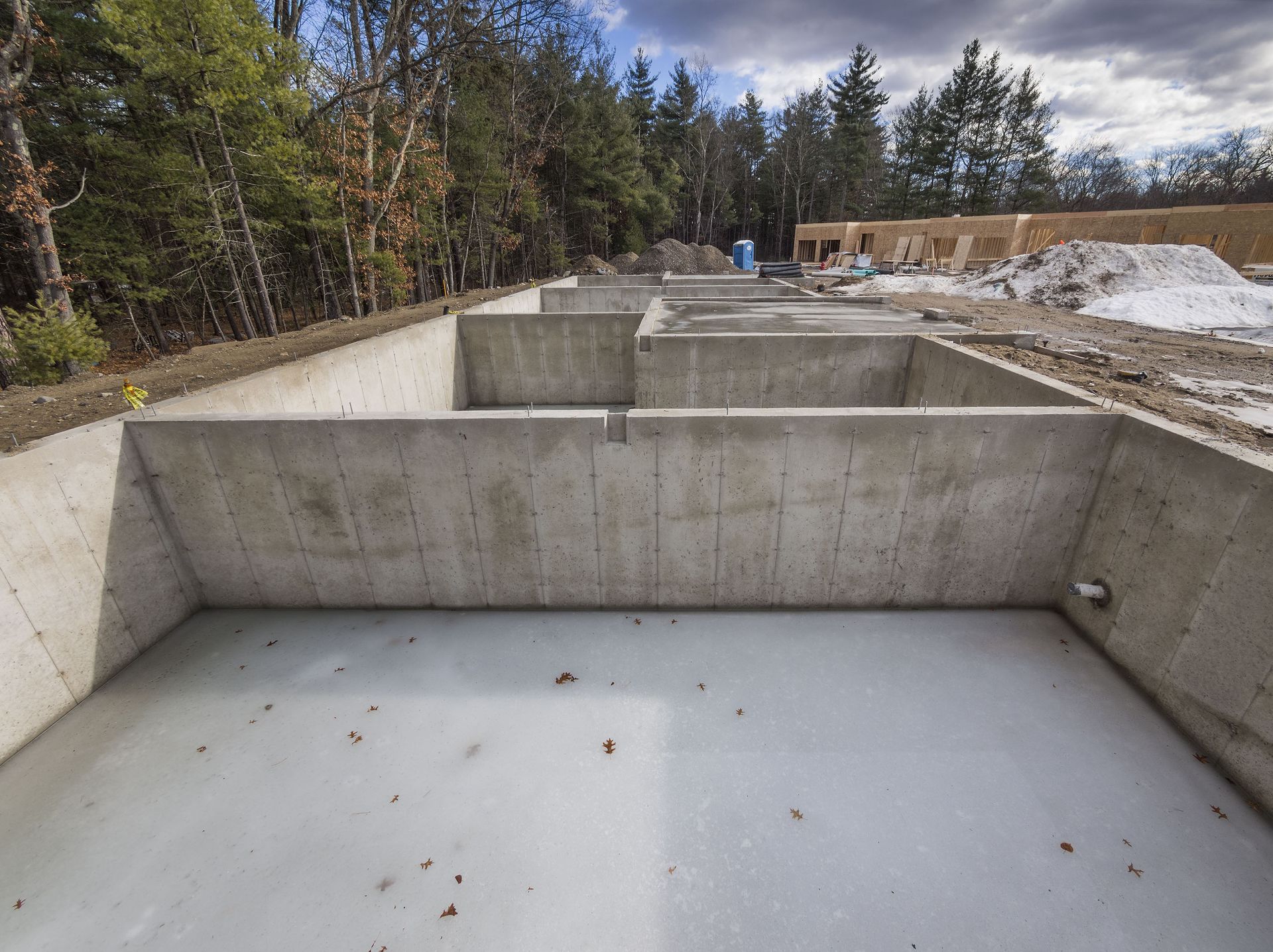 Concrete foundation of a house under construction, with interior walls and a smooth floor.