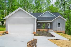 Gray house with white garage door, porch, and walkway.