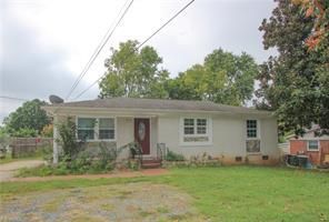 Small, single-story house with light-colored siding, a small front yard, and visible power lines.