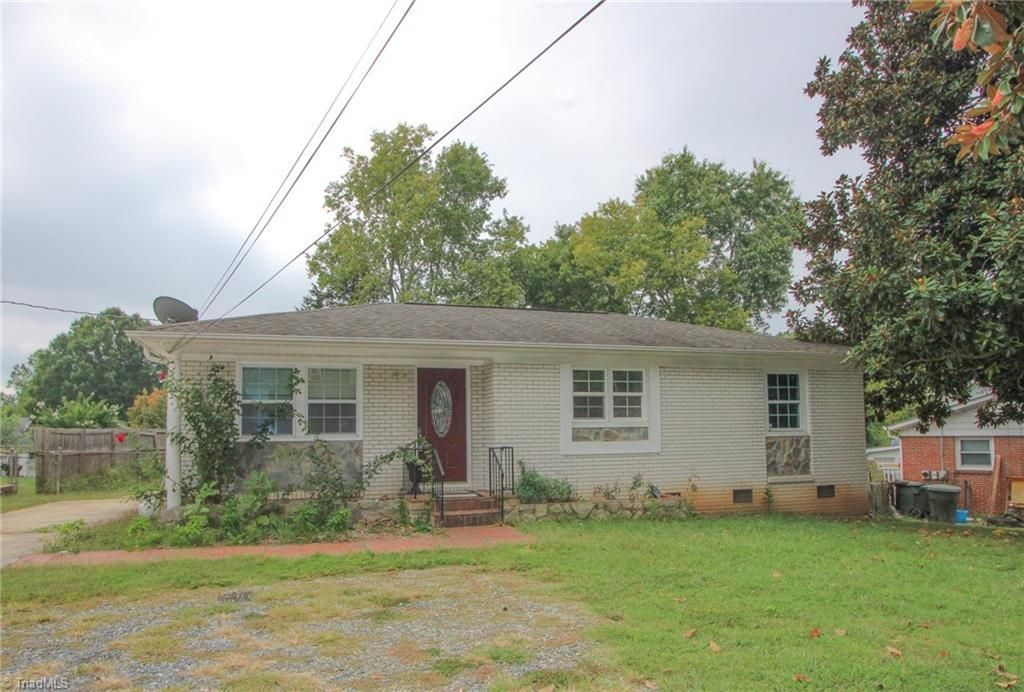 Small, single-story house with light-colored siding, a small front yard, and visible power lines.