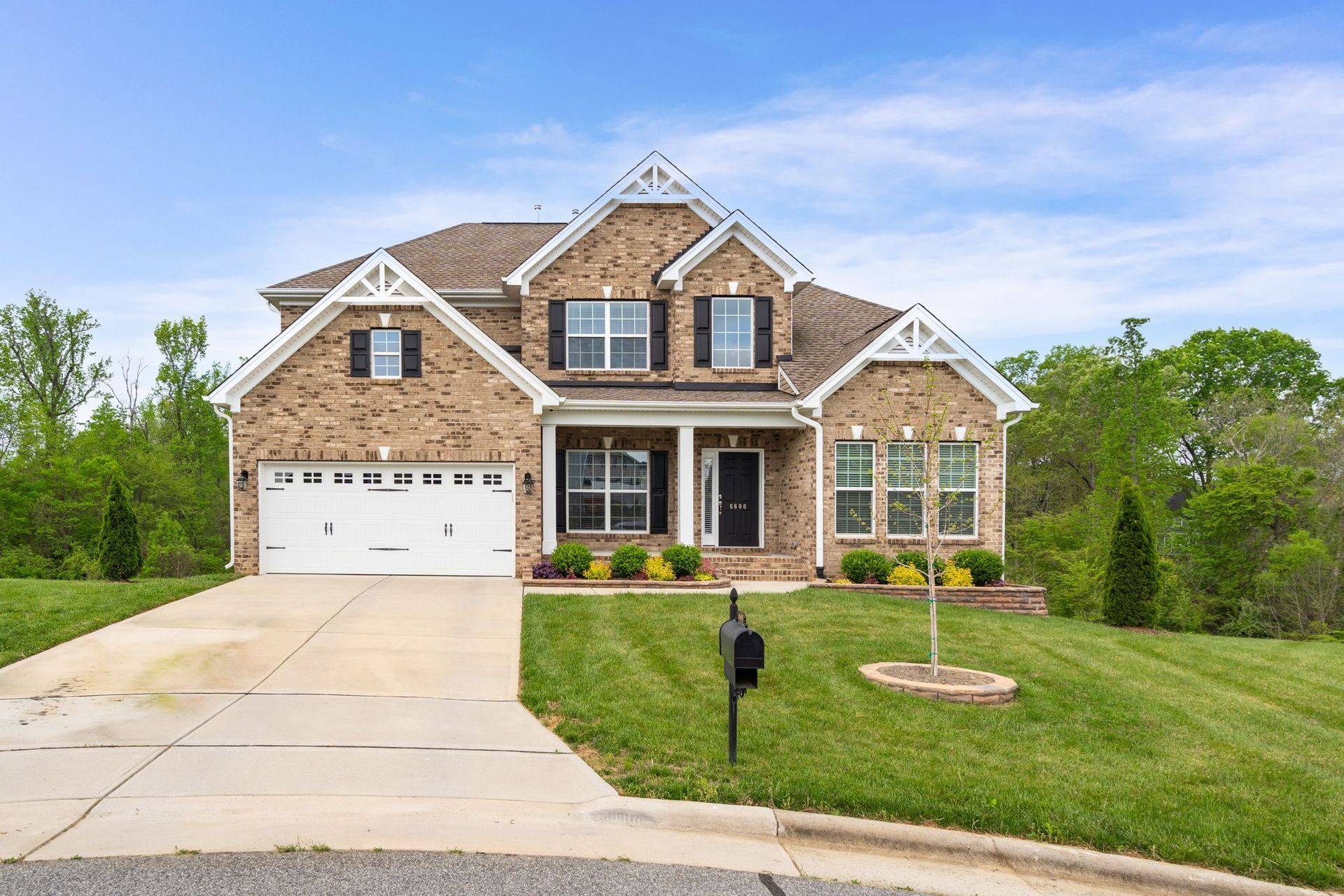 A large brick house with a large driveway and a mailbox in front of it.
