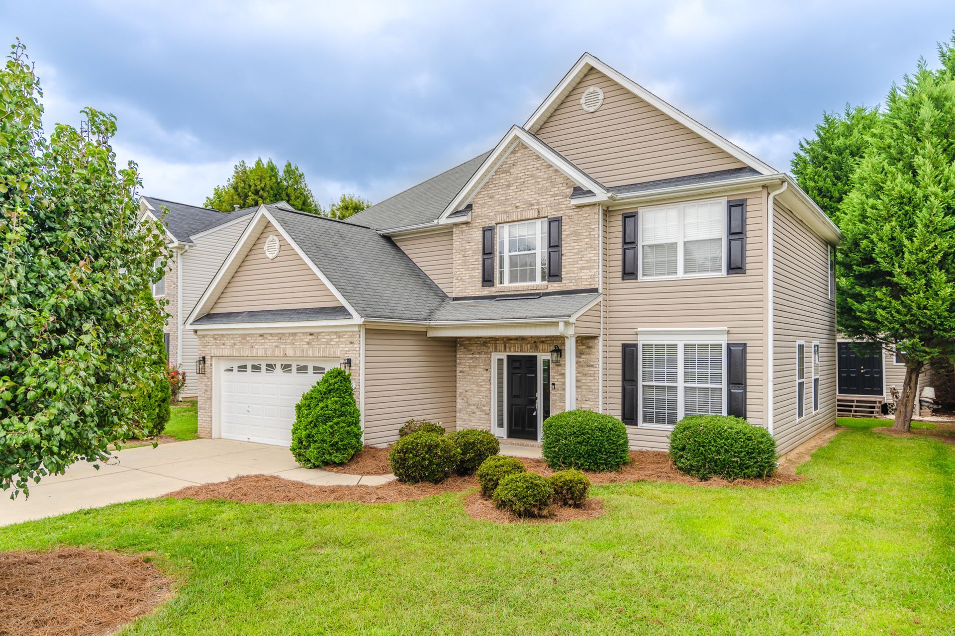 A large house with a lush green lawn and trees in front of it.