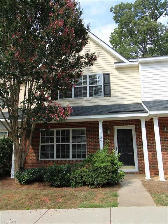 Two-story townhome with brick and siding. Large tree with pink flowers in front.