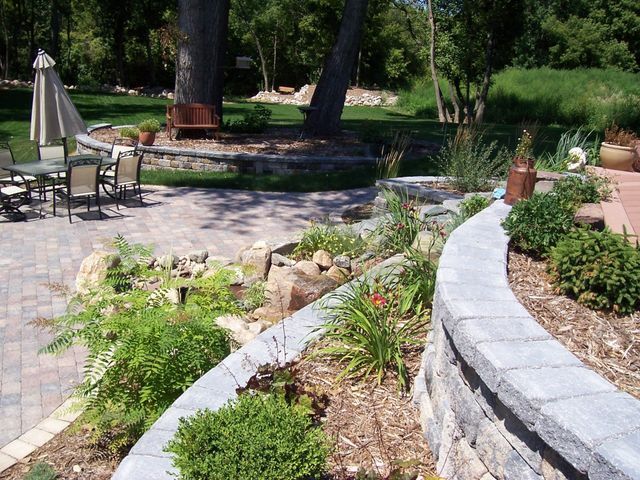 A patio with a table and chairs and a tree in the background