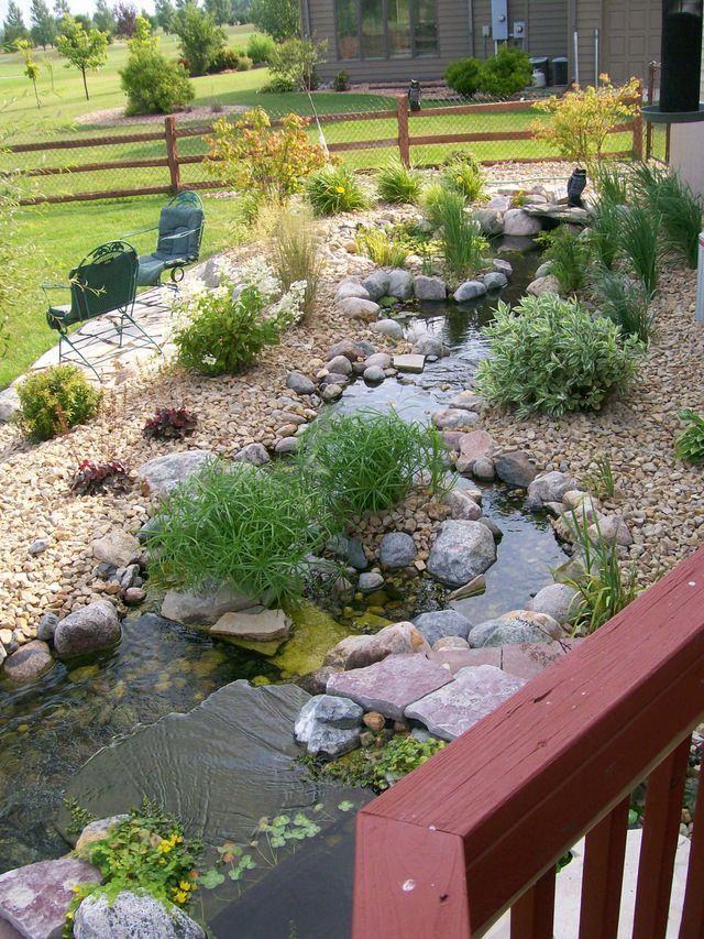 A backyard with a pond and a wooden fence