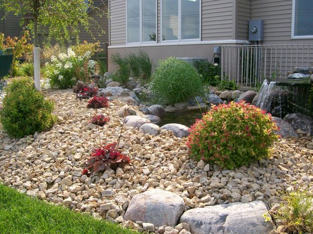 A garden with rocks and plants in front of a house.