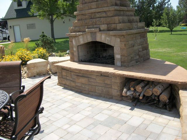 A brick fireplace with a bunch of logs underneath it
