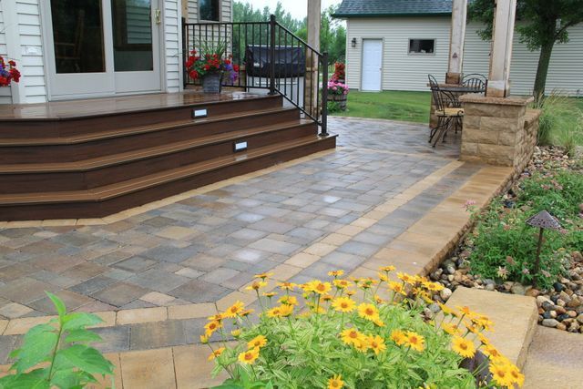 A patio with stairs and flowers in front of a house.