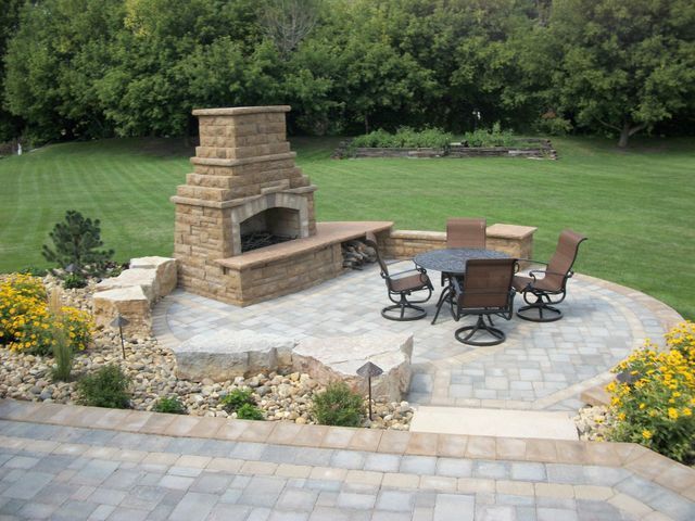 There is a fireplace and a table and chairs on the patio.