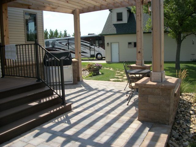 A patio with a pergola and a rv parked in the background