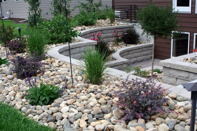 A garden with rocks and plants in front of a house.