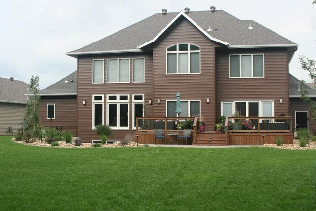 A large brown house with a large lawn in front of it