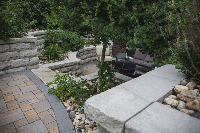 A patio with a stone wall and a tree in the middle of it.