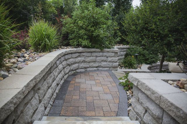 A stone walkway leading to a stone wall in a garden.
