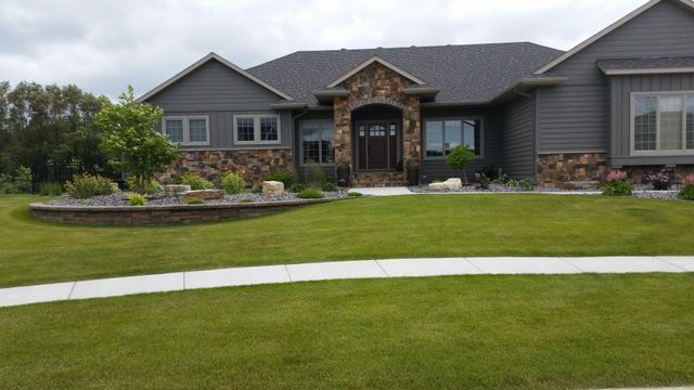 A large house with a lush green lawn and a walkway in front of it.