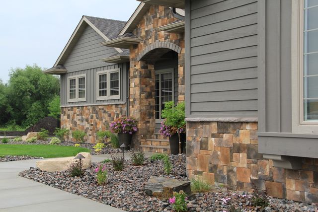 The front of a house with a stone facade and a concrete driveway.