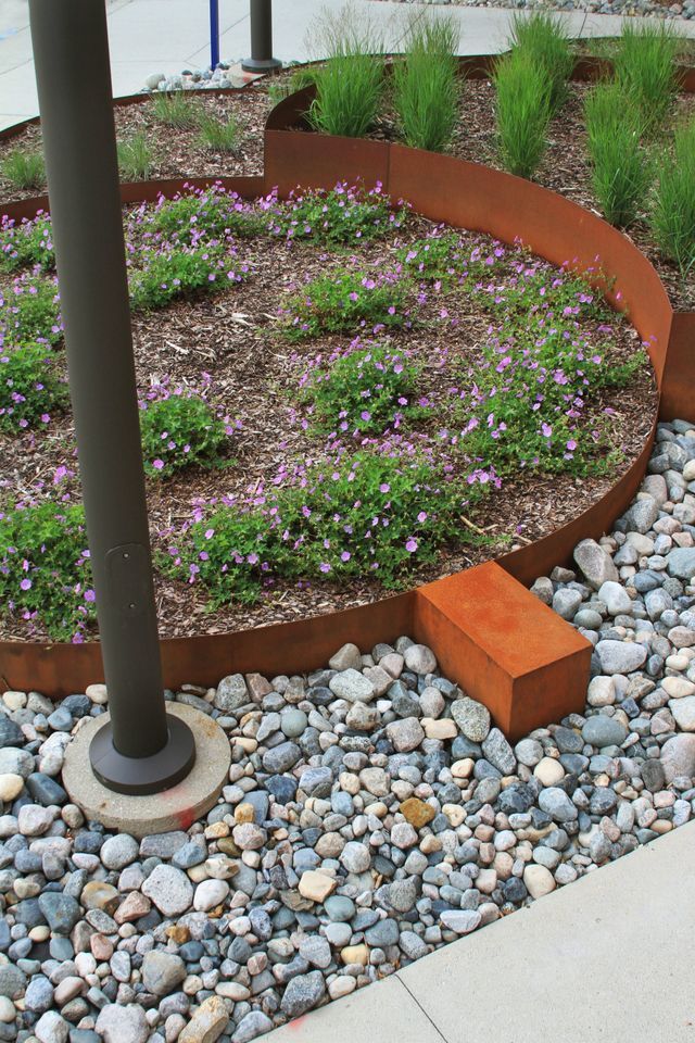 A garden with flowers and rocks and a metal edging