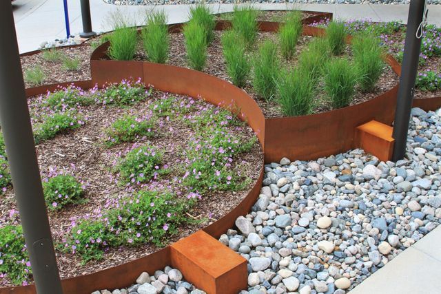A garden with flowers and rocks and a metal border