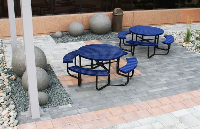 Two blue picnic tables with benches in a courtyard