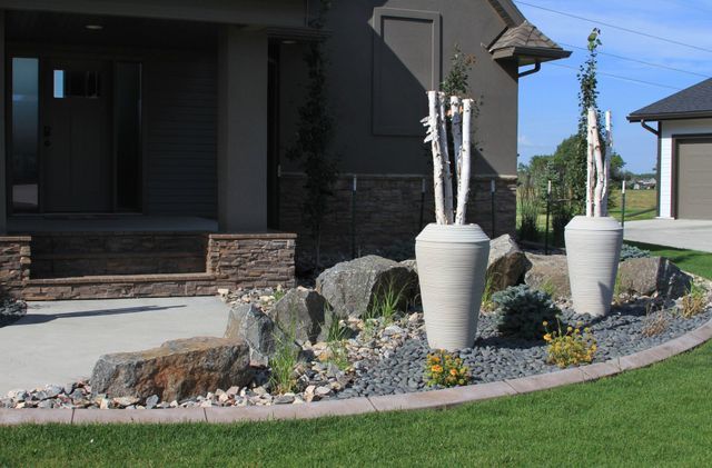 A house with a lot of rocks and plants in front of it.