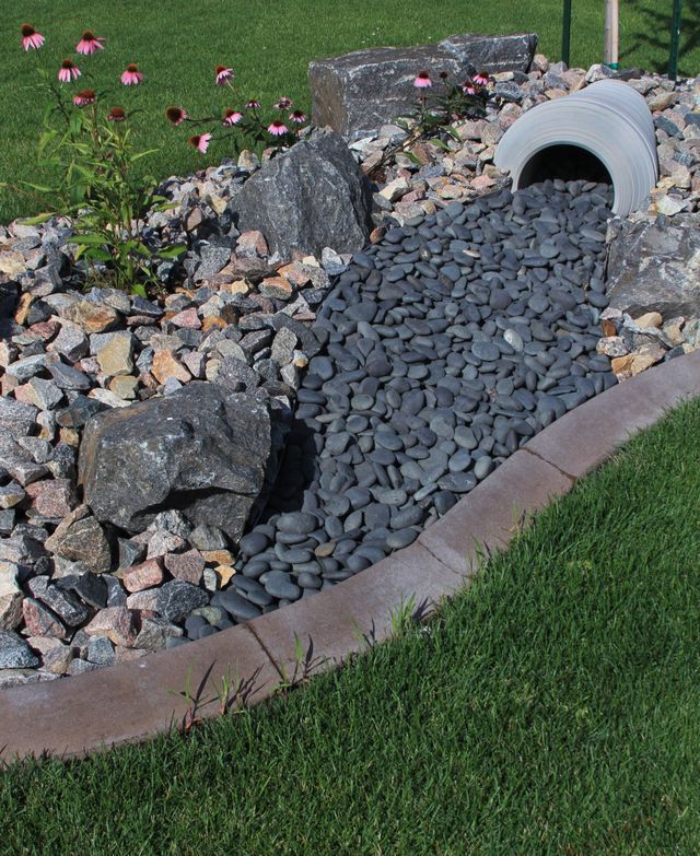 A drain pipe is coming out of a pile of rocks