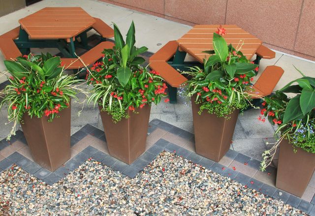A row of planters filled with flowers and plants next to a picnic table