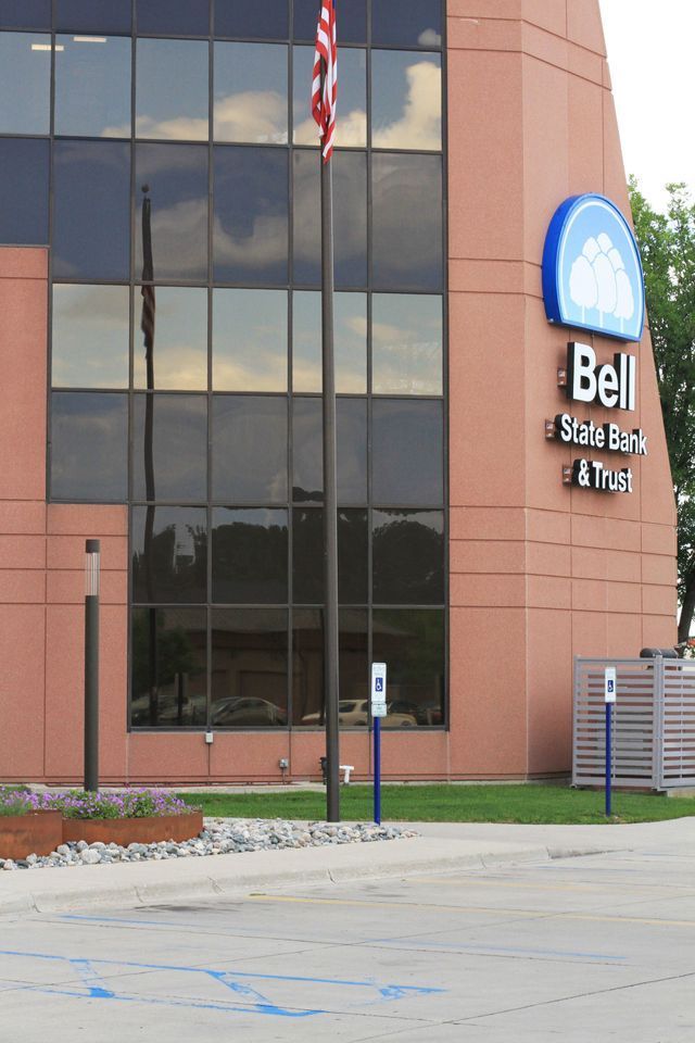 A bell state bank building with a flag in front of it