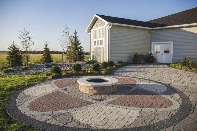 A fire pit in the middle of a patio in front of a house.
