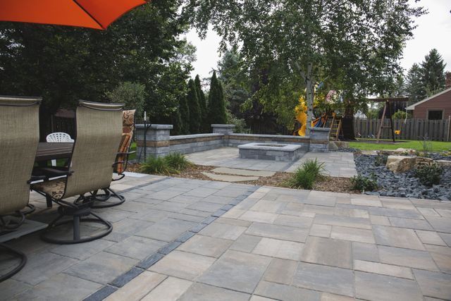 A patio with a table and chairs and an orange umbrella.