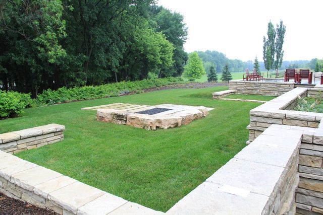 A fire pit in the middle of a lush green field
