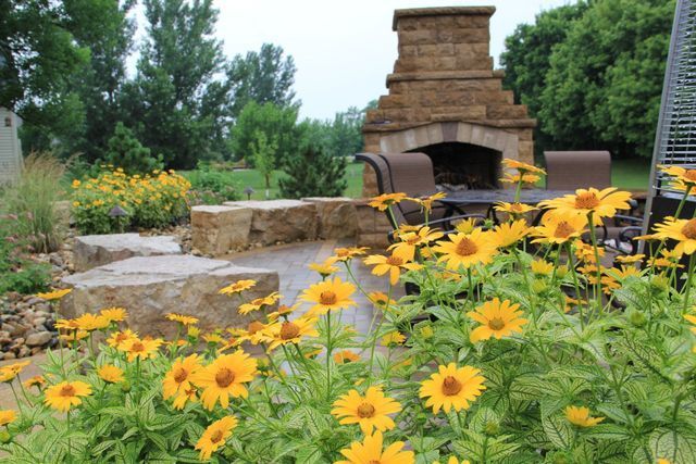 A fireplace is surrounded by yellow flowers in a garden.