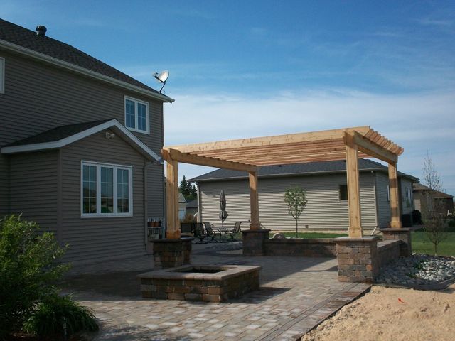A house with a pergola and a fire pit in front of it
