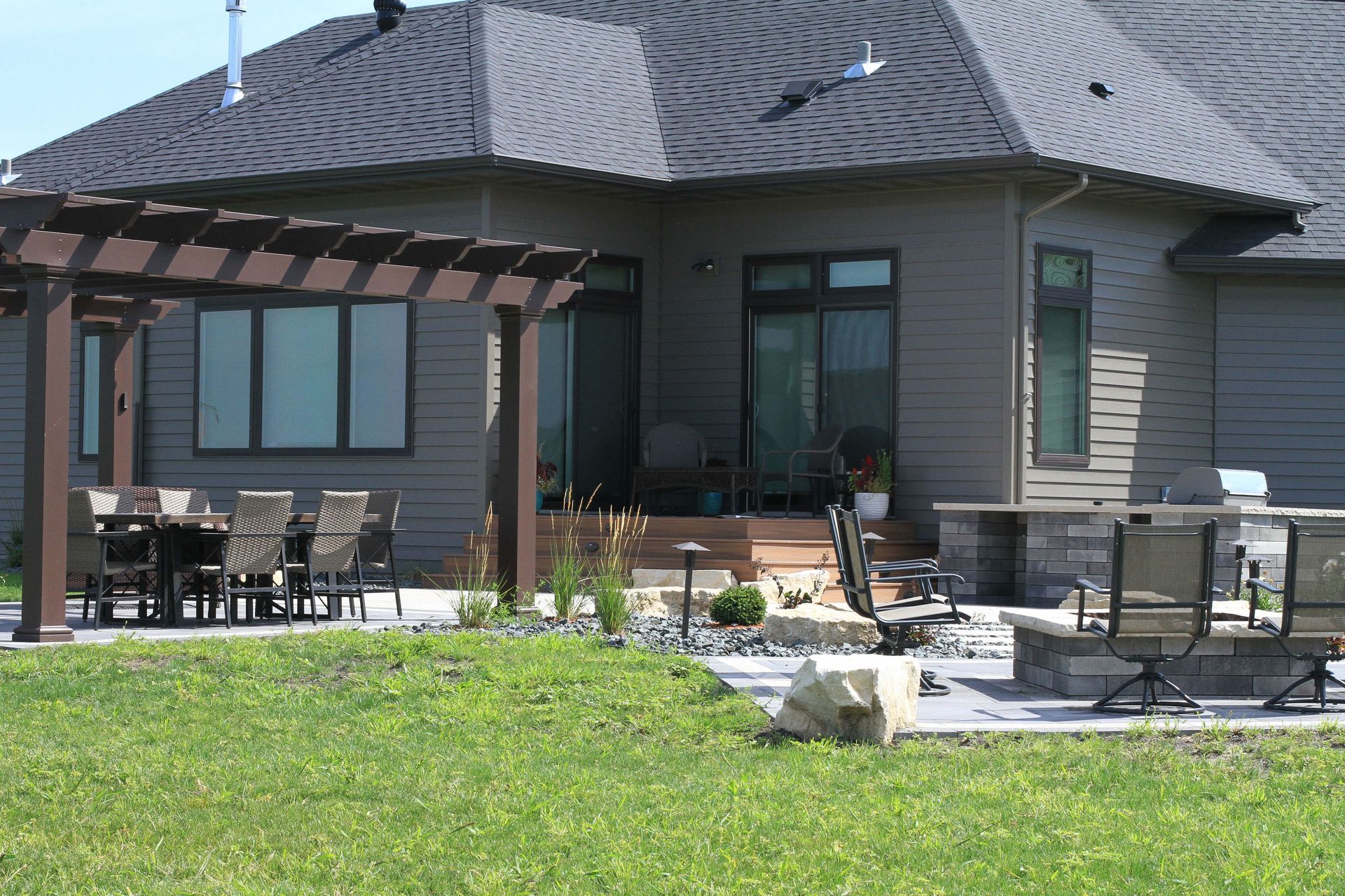 A house with a pergola and a table and chairs in front of it.