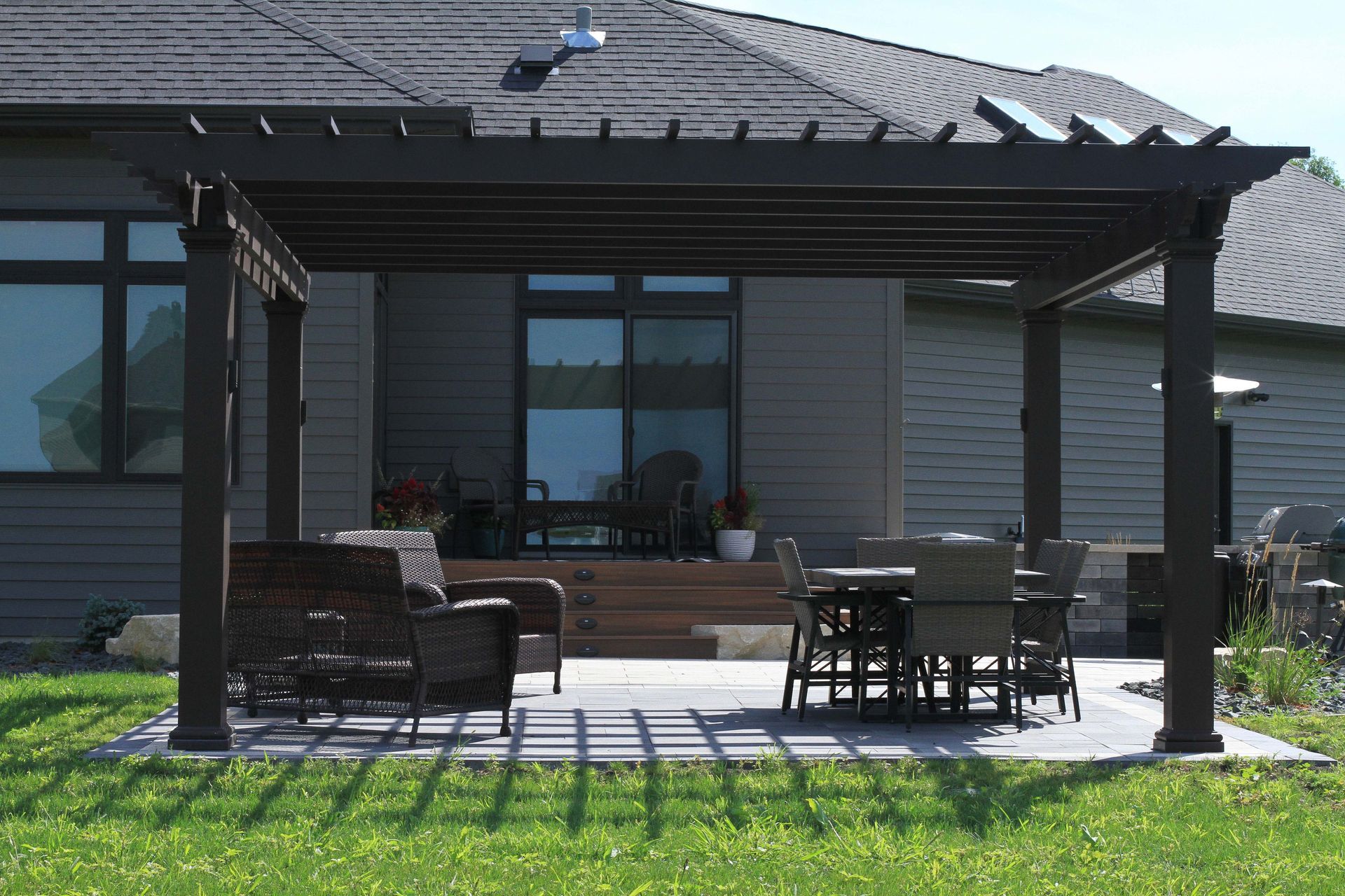 A pergola with a table and chairs in front of a house.