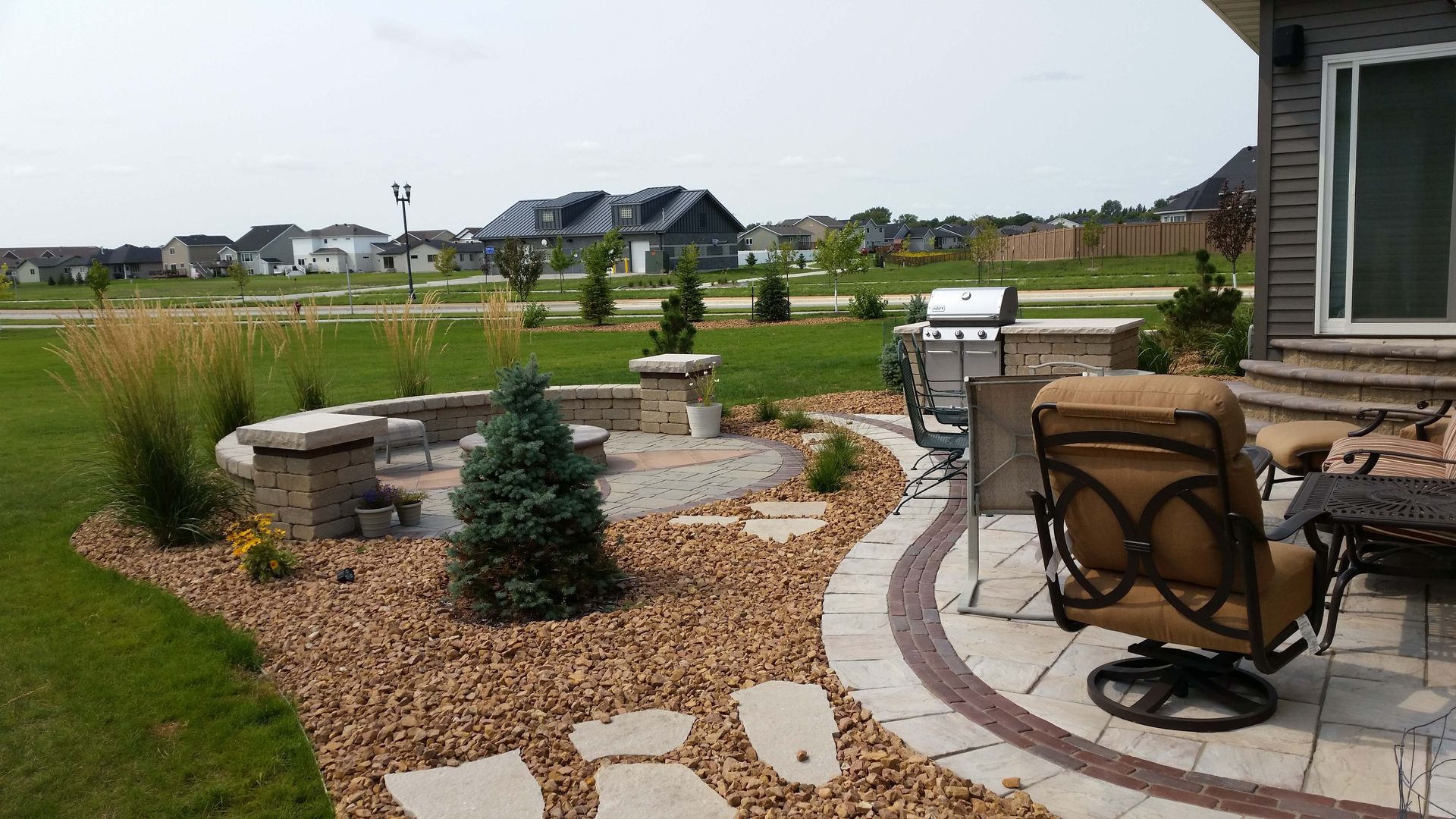 A patio with chairs and a grill in front of a house
