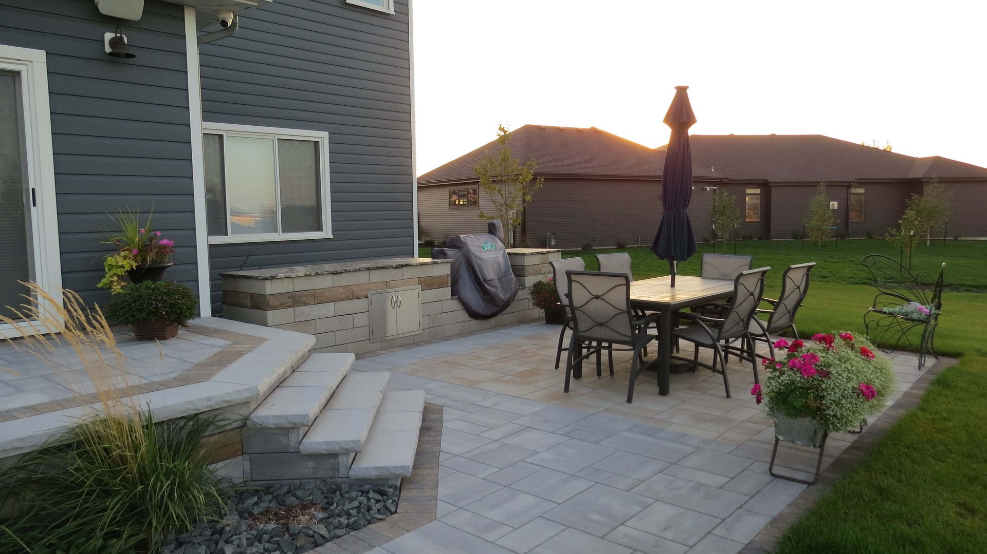 A patio with a table and chairs and an umbrella in front of a house