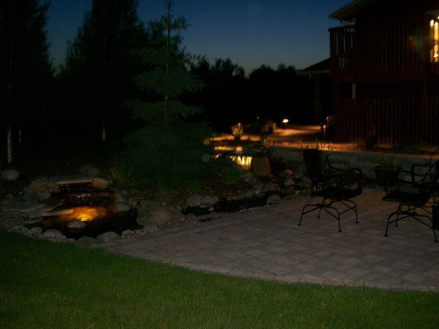 A patio area with chairs and a waterfall at night