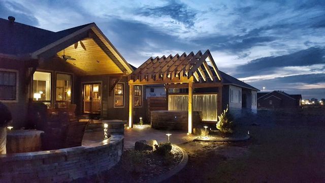 A house with a pergola in the backyard at night.
