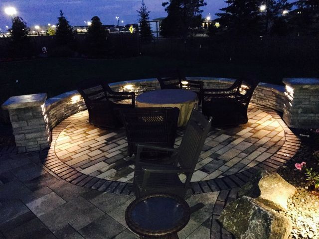 A brick patio with a table and chairs at night