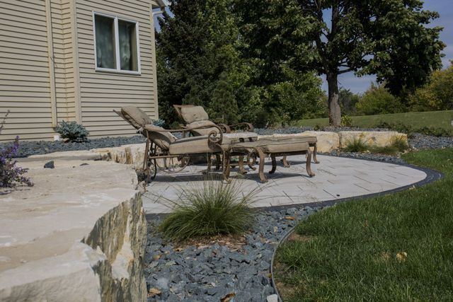 A patio with chairs and a table in front of a house.
