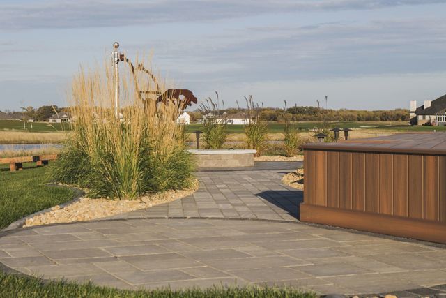 A hot tub is sitting on top of a patio next to a walkway.