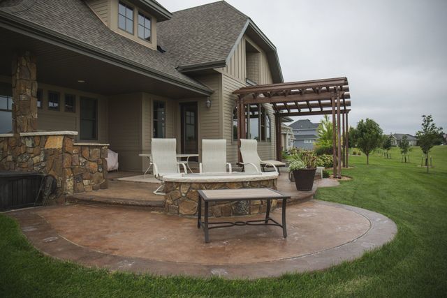 There is a patio with chairs and a table in front of a house.