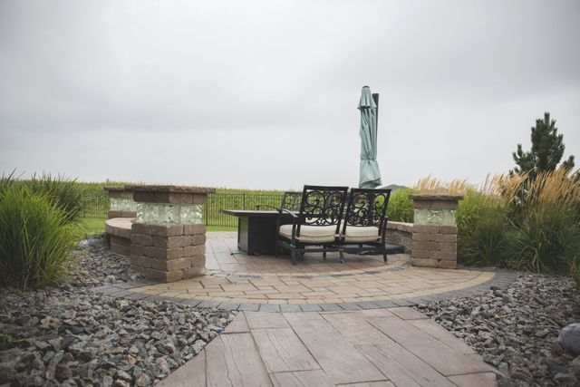 A patio with a table and chairs and an umbrella on a cloudy day.