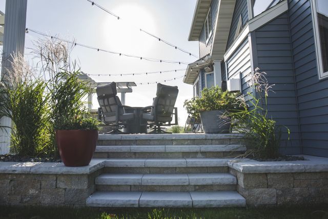 There is a patio with a table and chairs on it in front of a house.