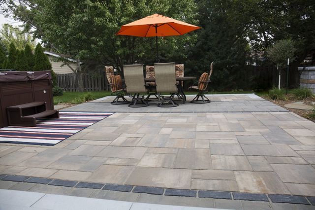A patio with a table and chairs and an orange umbrella